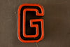 Vintage Industrial Letter "G" Black with Orange and Blue Paint, 2" tall (c.1940s) - thirdshift