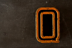 Vintage Industrial Letter "Q" Black with Light Orange and Green Paint, 2" tall (c.1940s) - thirdshift