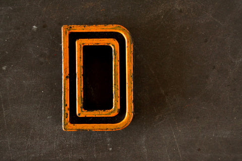 Vintage Industrial Letter "D" Black with Light Orange and Blue Paint, 2" tall (c.1940s) - thirdshift